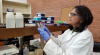 A photo of Sadhana Ravishankar looking at a petri dish